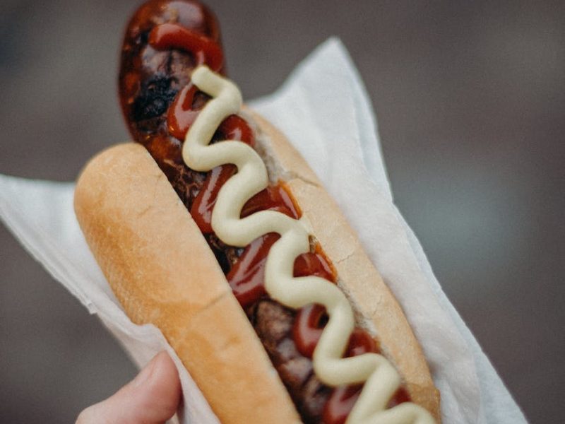 person holding hotdog sandwich with ketchup