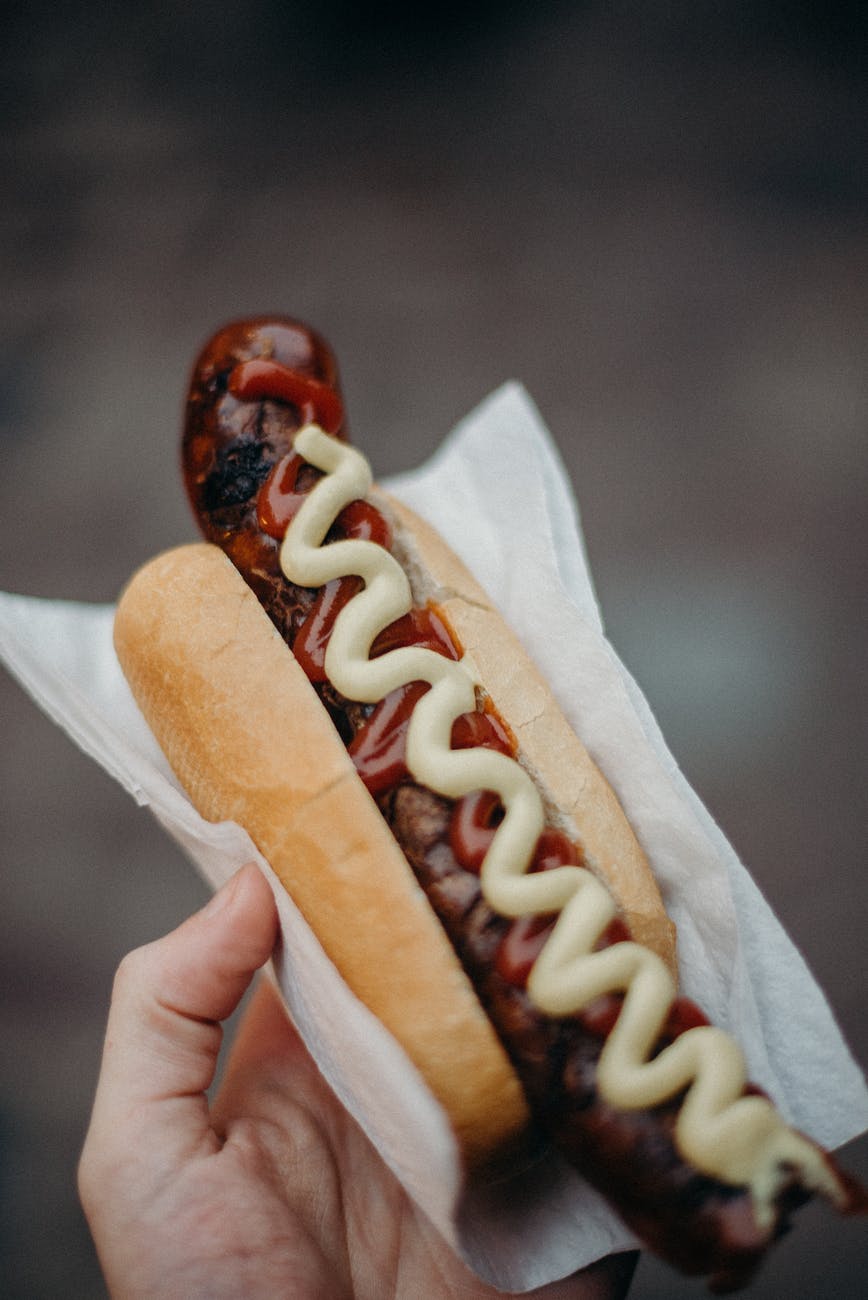 person holding hotdog sandwich with ketchup